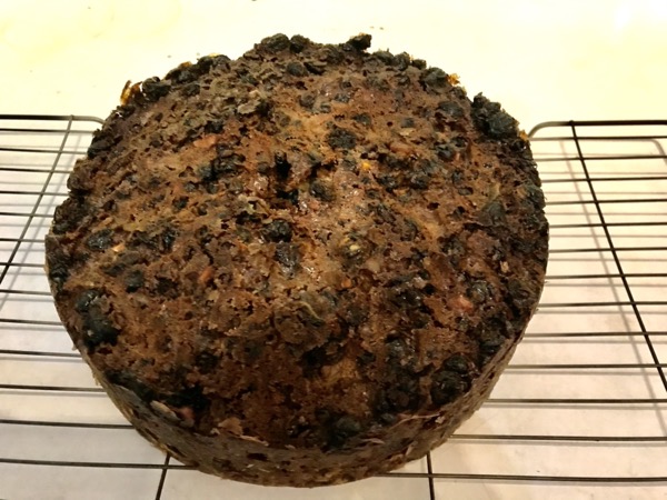 A Christmas cake (rich fruit cake) sitting on a cooling rack.